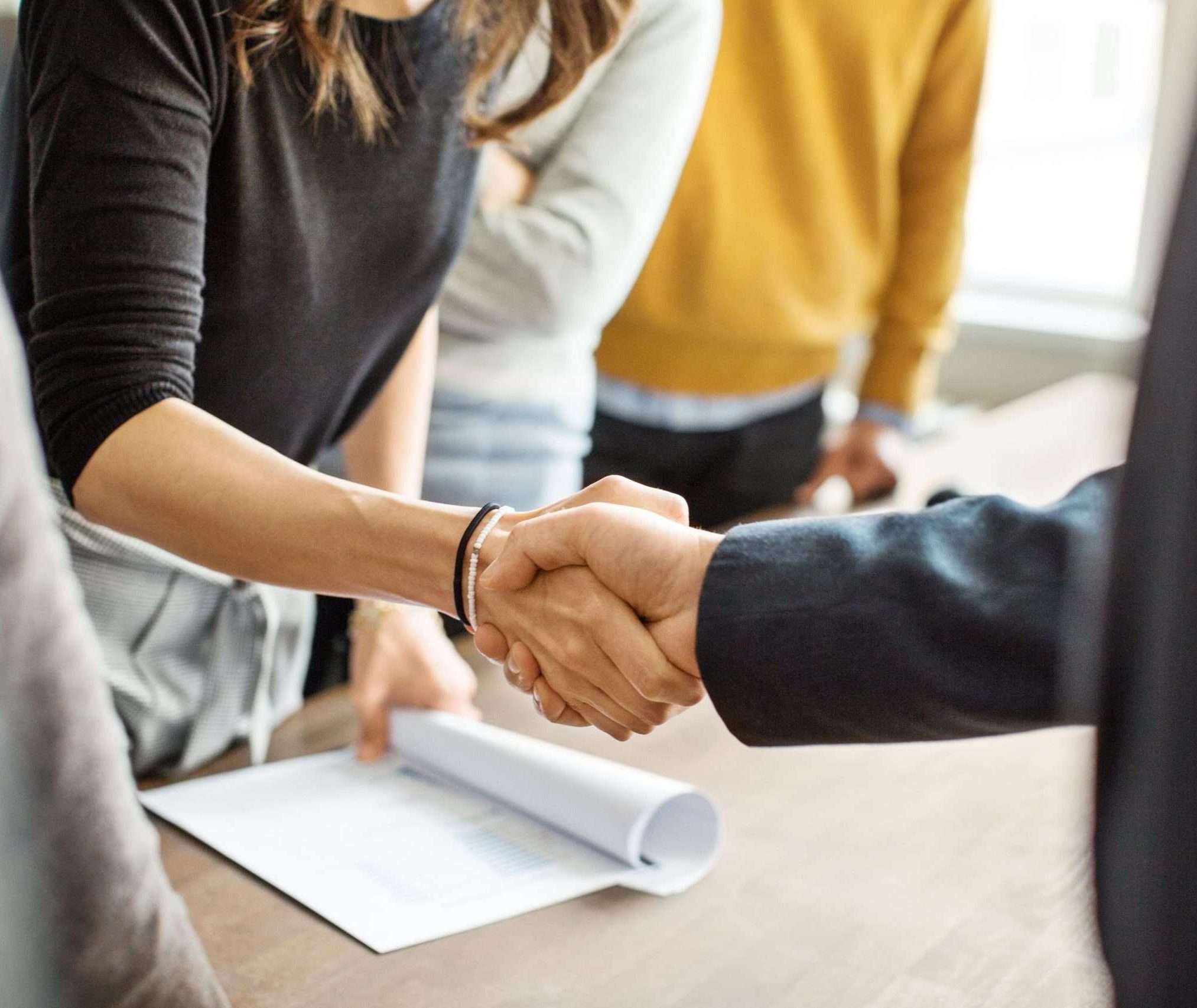 Cropped shot of businessman greeting a young professional around the table in office. Close up of business people shaking hands in office.